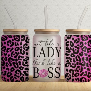 Op de afbeelding: Drie roze en zwarte tumblers met luipaardprint, houten deksels en heldere rietjes. De middelste tumbler heeft de tekst "act like a LADY think like a BOSS" met een roze lipafdruk.