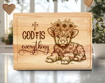 May include: A rectangular wooden chopping board with a carved design. The design features a Highland cow wearing a sunflower crown, and the text "GOD IS everything" with a cross and heart symbols. The board has a recessed edge.