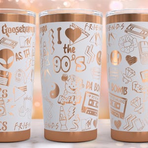 May include: Three white tumblers with a copper-coloured rim. Each tumbler features a different design with 90s-themed graphics in a copper colour. The graphics include a cassette tape, a heart, a boombox, a TV, and the words "I love the 90s".