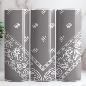 May include: Three gray stainless steel tumblers with a white bandana pattern. The tumblers are insulated and have a lid.