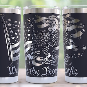 May include: Three black stainless steel tumblers with silver designs. One features a flag, another an eagle with a flag, and the third has a partial eagle and flag design. The words "We the People" are written on the tumblers.