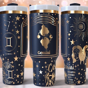 Puede incluir: Tres vasos de acero inoxidable con fondo azul marino y detalles dorados. Cada vaso presenta un signo del zodíaco diferente: Géminis, Géminis y Géminis. Los vasos tienen una tapa dorada y un asa.