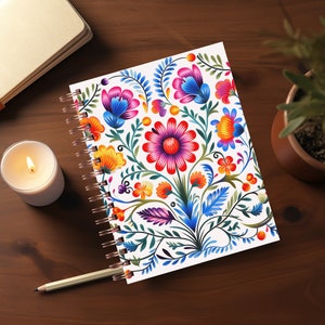 May include: A spiral bound notebook with a white cover featuring a colorful floral design. The flowers are red, orange, yellow, blue, and purple. The design is reminiscent of traditional folk art.