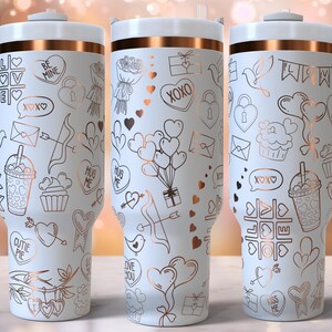 K&ouml;nnte beinhalten: Drei wei&szlig;e Edelstahlbecher mit ros&eacute;goldenen Akzenten und verschiedenen Designs zum Valentinstag. Die Designs beinhalten Herzen, Pfeile, Cupcakes und die Worte "Be Mine", "XOXO", "Hug Me" und "Cutie Pie".