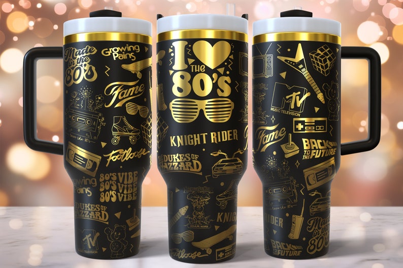 K&ouml;nnte beinhalten: Drei schwarze und goldene Edelstahlbecher mit verschiedenen Grafiken zum Thema der 1980er Jahre, darunter die Worte "I Love the 80's", "Knight Rider", "Zur&uuml;ck in die Zukunft" und "Dukes of Hazzard".