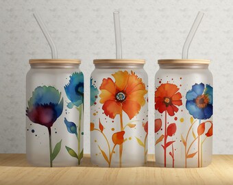 May include: Three frosted glass tumblers with bamboo lids and clear straws. Each tumbler features a watercolor floral design in shades of blue, orange, and red. The flowers are painted with a loose, artistic style, and the background is a soft, blurred white.