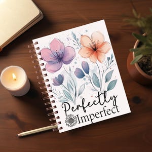 May include: A white spiral bound journal with a floral design and the text "Perfectly Imperfect". The flowers are pink, purple, and orange.