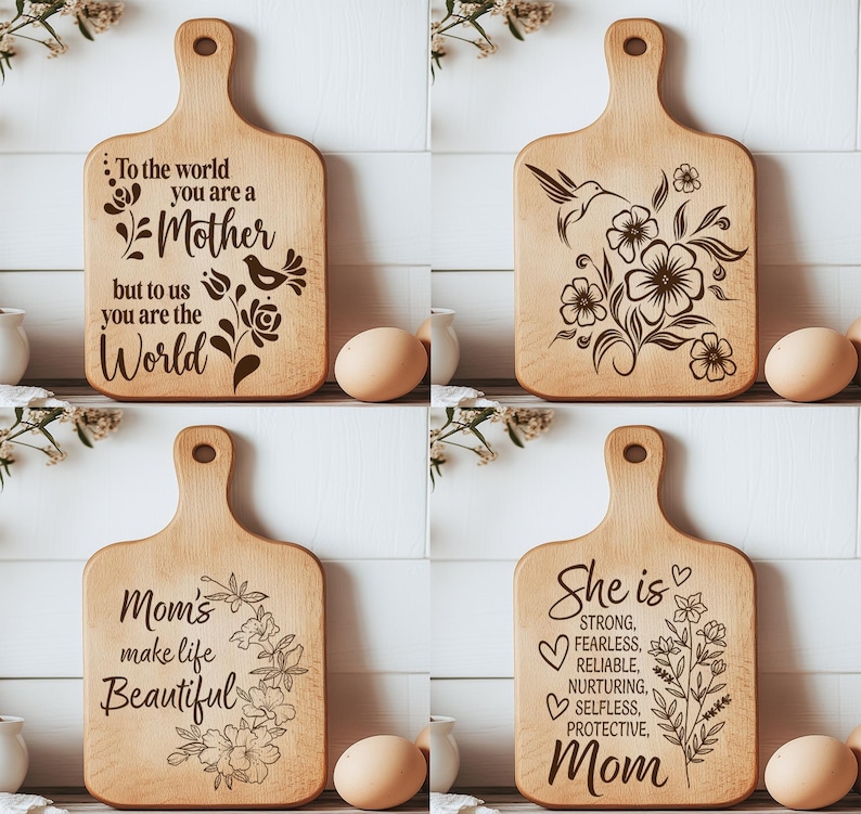 K&ouml;nnte beinhalten: Vier Holzschneidebretter mit eingravierten Designs und Text. Ein Brett tr&auml;gt die Aufschrift "To the world you are a Mother but to us you are the World." Ein anderes zeigt einen Kolibri und Blumen. Ein drittes sagt "Mom's make life Beautiful." Das letzte sagt "She is Mom."