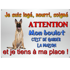 Op de afbeelding: Rechthoekig metalen bord met een lichtgrijze achtergrond, een zittende hond en Franse tekst in verschillende kleuren. De tekst luidt: "Je suis logé, nourri, soigné, ATTENTION, Mon boulot, C'EST DE GARDER LA MAISON, et je tiens à ma place!"