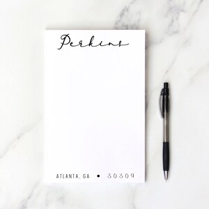 May include: A white notepad with the name "Perkins" written in black cursive script at the top. The address "ATLANTA, GA  30309" is printed in black at the bottom of the notepad.