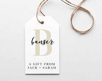 Op de afbeelding: Een wit cadeau-etiket met een beige letter "B" en de tekst "banse" in zwarte cursieve letters. Onder de letter staat de tekst "A GIFT FROM JACK + SARAH".