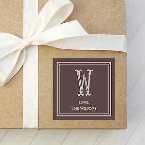 May include: A brown square gift tag with a white border and a white monogram of the letter "W" inside. The text "Love, The Wilsons" is printed in white below the monogram.