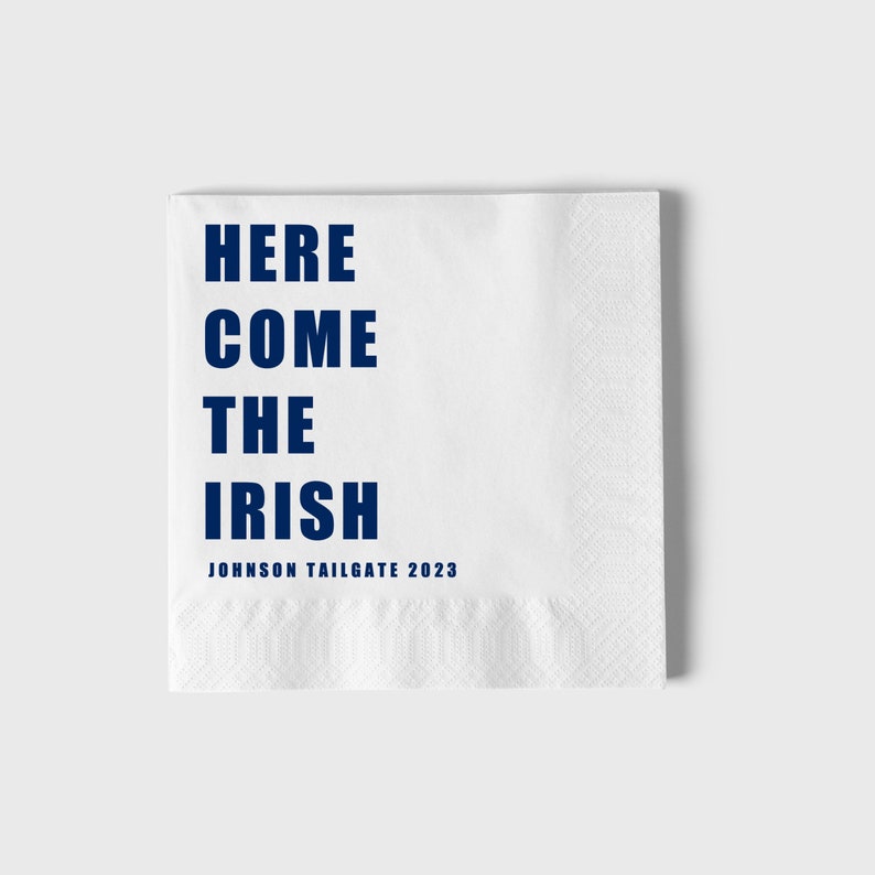 May include: White paper napkin with the text "HERE COME THE IRISH" in blue lettering and "JOHNSON TAILGATE 2023" in smaller blue lettering below.