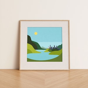 Op de afbeelding: Een ingelijst afdruk van een gestileerde illustratie van een kasteel aan een meer, omringd door groene heuvels en een blauwe lucht met een gele zon.