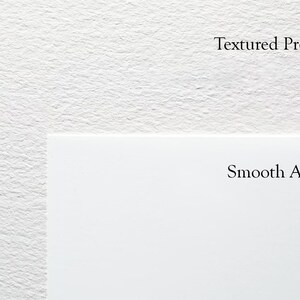 Op de afbeelding: Close-up van twee witte oppervlakken, een met textuur en het label "Textured Premium" en de andere glad en met het label "Smooth Archival".