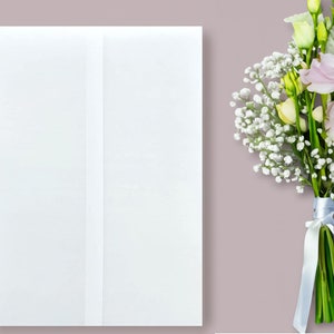 Pu&ograve; includere: Una busta bianca con una piega verticale al centro, accanto a un mazzo di fiori bianchi e rosa legati con un nastro blu chiaro.