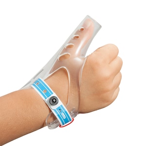 Puede incluir: Una férula para el pulgar de plástico transparente con una correa azul y blanca. La férula está diseñada para inmovilizar el pulgar y ayudar en la curación.
