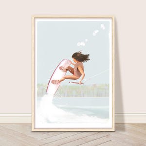 May include: A woman in a brown swimsuit is wakeboarding on a pink and white wakeboard. She is wearing a brown swimsuit and has long brown hair. The wakeboard is in the air and she is holding onto a rope. The water is blue and there are white waves behind her.