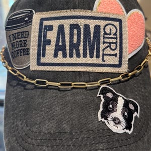 May include: A black denim baseball cap with a gold chain, a pink heart, a coffee cup patch that says "I need more coffee", a dog patch, and a patch that says "FARM GIRL".