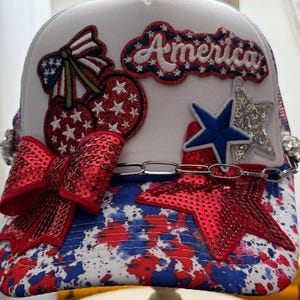 Cerezas y el 4 de julio. Gorra de camionero patriótica para mujer. Ropa de verano. Efecto salpicado. Rojo, blanco y azul.