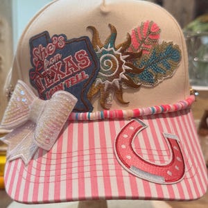 She’s from Texas !!   Ladies trucker hat in a pink and ivory cotton stripe .    Multiple patches .    Beaded chain .