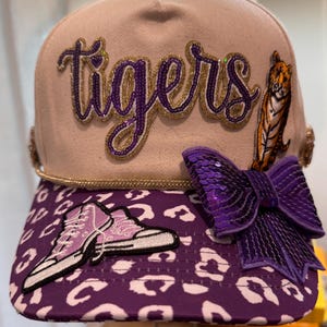 Canvas balpet in crème en paars.   Tijgers.   Dames en tienermeisjes.   Hoed met paardenstaart.   Meerdere patches.   Steentjes.