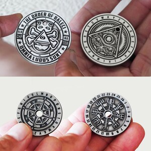 Peut inclure: Trois jetons en m&eacute;tal argent&eacute; avec des motifs diff&eacute;rents. Le premier jeton repr&eacute;sente un cr&acirc;ne et des os crois&eacute;s avec un &oelig;il dans un triangle, entour&eacute; d'un texte qui dit "THE ORDER OF BALECI * VI * ALD CHP * OMNIALUDUS SUNT * AI * HA TER *." Le deuxi&egrave;me jeton repr&eacute;sente un &oelig;il dans un triangle entour&eacute; d'un cercle de texte qui dit "RSTUVWXYZABCDEFGHIJKLMNOP." Le troisi&egrave;me jeton repr&eacute;sente une boussole avec un cercle de chiffres autour du bord, de 1 &agrave; 26.