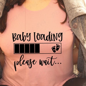 Pode incluir: Uma camiseta rosa com o texto "Baby Loading" e uma barra de progresso com pegadas de bebê. O texto "Please wait..." está abaixo da barra de progresso.