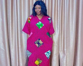 Könnte beinhalten: Ein leuchtend pinkfarbenes, knielanges Kleid mit V-Ausschnitt und kurzen Ärmeln. Das Kleid hat bunte geometrische Patches und ein Wirbelmuster. Es hat Taschen und wird von einer Person getragen.