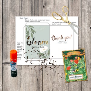 May include: A seed packet design with the word "bloom" and "thank you" printed on it. A packet of wildflower seeds, a glue stick, gold scissors, and scattered seeds are also visible. The packet design includes instructions for assembly.