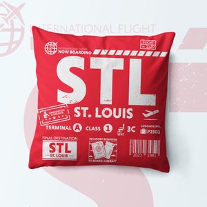 May include: A square red throw pillow featuring a white graphic design resembling an airline boarding pass for St. Louis, STL. The print includes text such as INTERNATIONAL FLIGHT, NOW BOARDING, TERMINAL A, CLASS 1, SEAT 3C, and LUGGAGE NO. P2301.