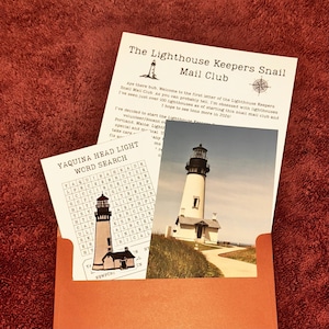 Peut inclure: Une enveloppe orange contenant une carte postale et un jeu de mots cachés. La carte postale présente une photographie d'un phare blanc avec un sommet noir. Le jeu de mots cachés est intitulé "YAQUINA HEAD LIGHT WORD SEARCH". L'enveloppe contient également une lettre intitulée "The Lighthouse Keepers Snail Mail Club".