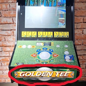 May include: A black arcade game cabinet with the text "Golden Tee 3D Golf" on the top and bottom. The game features a golf course display and control panel with buttons and a joystick.
