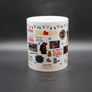 May include: White ceramic mug with a colorful design featuring the movie Home Alone. The mug has a festive Christmas theme with lights, snowflakes, and a wreath. It includes quotes from the movie, such as "Merry Christmas ya filthy animal" and "I made my family disappear."