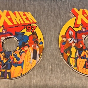 May include: Two yellow and red round X-Men '97 pinback buttons featuring a group of cartoon superheroes, including Wolverine, Cyclops, Storm, and Professor X.