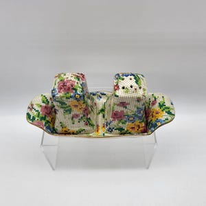 May include: A set of two white ceramic salt and pepper shakers with a floral design. The shakers are on a matching tray with a gold trim.