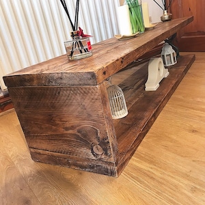 May include: A rustic wooden coffee table with a lower shelf. The table has a dark brown stain and is made of reclaimed wood. The table is decorated with a birdcage, a lantern, and a decorative object.