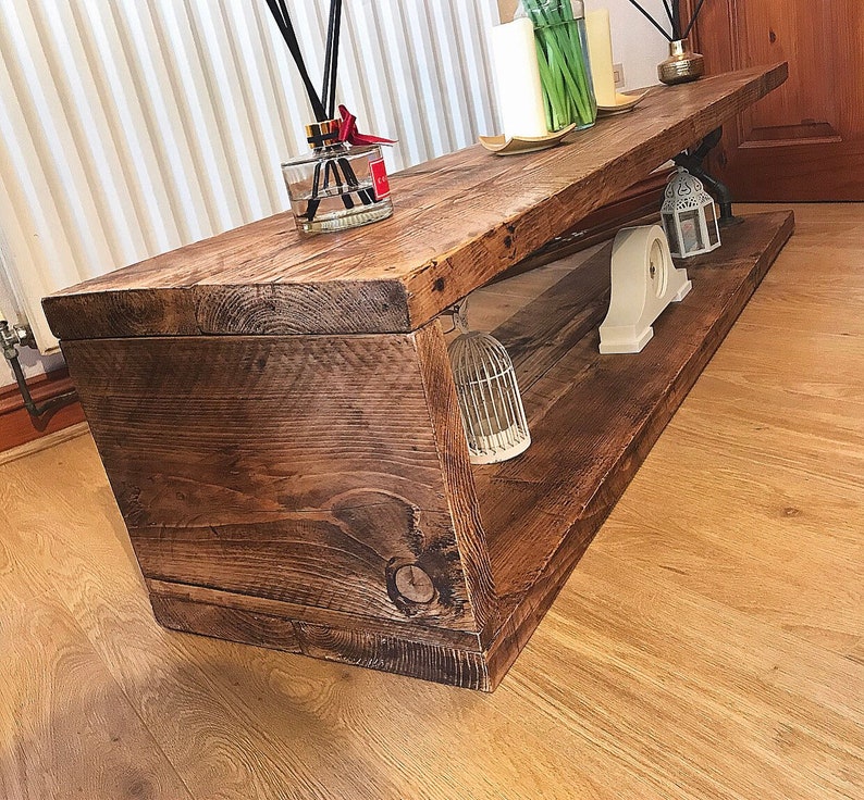 May include: A rustic wooden coffee table with a lower shelf. The table has a dark brown stain and is made of reclaimed wood. The table is decorated with a birdcage, a lantern, and a decorative object.