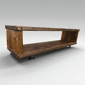 Puede incluir: Estanter&iacute;a rectangular de madera con acabado marr&oacute;n oscuro. La estanter&iacute;a tiene un centro hueco y est&aacute; soportada por cuatro peque&ntilde;os pies redondos de metal. La veta de la madera es visible, lo que a&ntilde;ade a la est&eacute;tica natural.
