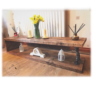 May include: A rustic wooden shelf unit with two shelves and black metal pipe legs. The shelf is decorated with a clock, a birdcage, a lantern, candles, and a vase of yellow daffodils. The shelf is labeled "Gooding Wooding Bespoke Handcrafted 2020".