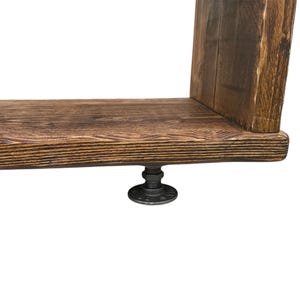 Puede incluir: Estanter&iacute;a r&uacute;stica de madera con acabado marr&oacute;n oscuro. Se apoya en una base de metal negro con conexiones de tuber&iacute;a. La veta de la madera es visible, lo que a&ntilde;ade a la est&eacute;tica natural. La estanter&iacute;a est&aacute; dise&ntilde;ada para montaje en pared.