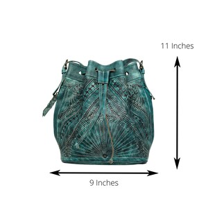 May include: Teal blue leather bucket bag with intricate floral and star-shaped embossed designs. The bag measures 11 inches tall and 9 inches wide.