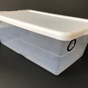 May include: A clear plastic storage container with a white lid. The lid has two small black circles on the top.