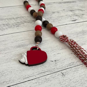 Hot cocoa themed wood bead garland. Dark brown, brown, red and white beads. Mug shaped tag with red and white tassel.