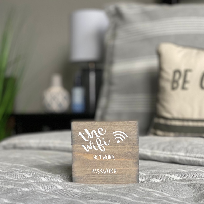 Puede incluir: Un letrero de madera con el texto "the wifi" y un s&iacute;mbolo de wifi. El letrero tambi&eacute;n dice "network password".