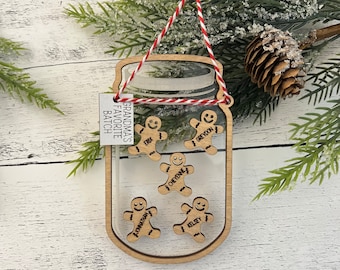 Puede incluir: Adorno navideño de madera con forma de tarro de cristal con una etiqueta que dice "Grandma's Favorite Batch". Dentro del tarro hay cinco hombres de jengibre con los nombres Erik, Greydon, Cheyenne, Jonathan y Kelsey.