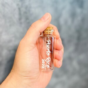 Mini glass bottle with honeymoon destination on it applied with vinyl in a hand for size comparison.