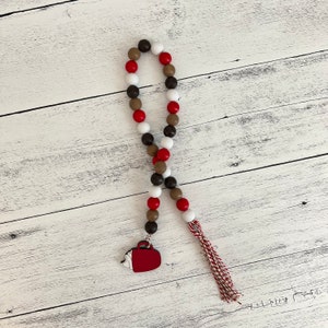 Hot cocoa themed wood bead garland. Dark brown, brown, red and white beads. Mug shaped tag with red and white tassel.