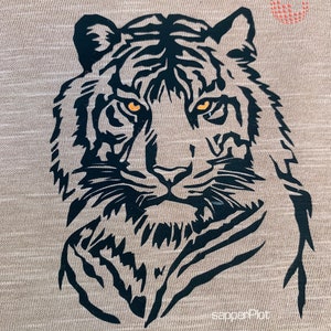 Puede incluir: Una ilustración en blanco y negro de la cara de un tigre sobre un fondo beige. El tigre tiene ojos naranjas y una expresión feroz.