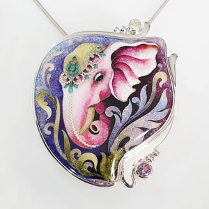 Op de afbeelding: Een zilveren hanger met een gedetailleerd emaille schilderij van een olifant met paarse, roze en groene accenten. De olifant is omringd door bloemmotieven en bezet met kleine edelstenen.